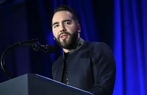 Aunque la seguridad continúa siendo el principal logro del gobierno del presidente Nayib Bukele, cada vez más salvadoreños expresan preocupación por el impacto de las medidas de ajuste económico implementadas por su administración, en medio de un programa acordado con el Fondo Monetario Internacional (FMI). Como parte del plan suscrito en 2024 para acceder a un financiamiento de hasta US$1,400 millones, el Gobierno ejecutó recortes en el empleo público y otras medidas fiscales destinadas a reducir una deuda que ronda el 90 % del Producto Interno Bruto (PIB). Uno de los casos es el de Lilian Hernández, psicóloga de 59 años, quien perdió su empleo en una institución de protección a la mujer y tuvo que adelantar su jubilación. Actualmente subsiste con una pensión de US$432 mensuales, con la que también sostiene a su madre, diagnosticada con Alzheimer. Aunque no existen cifras oficiales, economistas estiman que alrededor de 15,000 empleados públicos han sido despedidos desde 2024, mientras que organizaciones sindicales aseguran que la cifra supera los 47,000 desde la llegada de Bukele al poder en 2019. Pese a estas críticas, Bukele mantiene niveles de aprobación superiores al 80 %, impulsados por su política de seguridad, que redujo la tasa de homicidios a 1.3 por cada 100,000 habitantes en 2025. Sin embargo, una encuesta de la Universidad Centroamericana revela que siete de cada diez salvadoreños consideran la situación económica como el principal problema del país. La economía salvadoreña registró un crecimiento de 3.9 % en 2025, uno de los más bajos de Centroamérica, y proyecciones del grupo financiero Cibest indican que este año podría desacelerarse hasta 2.9 %, debido a una menor demanda de los hogares. El incremento del costo de vida también ha afectado el consumo de las familias. La inflación interanual alcanzó 2.76 % en junio, mientras que la canasta básica ronda los US$260 mensuales, obligando a muchos hogares a reducir gastos en alimentos. Para mitigar ese impacto, el Gobierno creó una red de agromercados subsidiados, al tiempo que apuesta por sectores como la construcción y el turismo, que crecieron 24 % y 10 %, respectivamente, durante 2025. Analistas advierten que, si Bukele obtiene un nuevo mandato, podría profundizar el ajuste fiscal para reducir el déficit, mientras el país continúa dependiendo en gran medida de las remesas, que representan cerca de una cuarta parte del PIB, y busca atraer mayor inversión extranjera.
