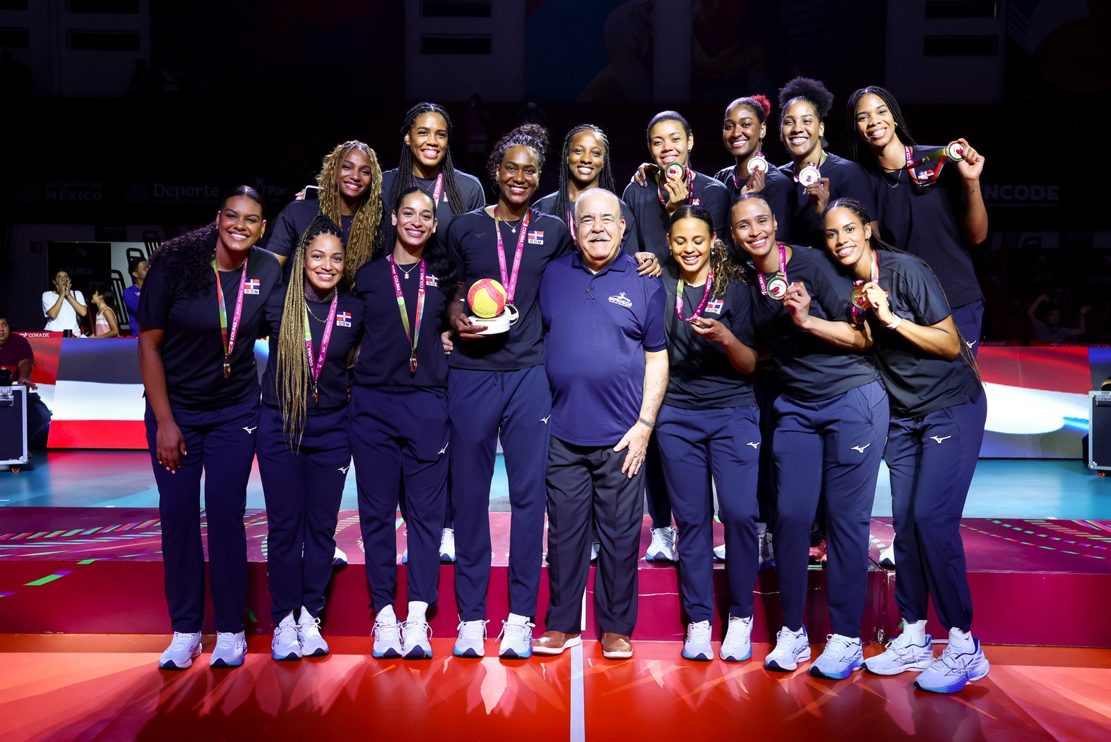 La Selección Nacional de Voleibol Femenino de República Dominicana (Las Reinas del Caribe) debutará este domingo 2 de agosto frente a Costa Rica, a las 8:00 p. m., en el Palacio de Voleibol “Ricardo Gioriber Arias”, ubicado en el Centro Olímpico Juan Pablo Duarte, para iniciar la defensa de su título en el Torneo de Voleibol de los XXV Juegos Centroamericanos y del Caribe Santo Domingo 2026. Plantel confirmado El director técnico del equipo, Marcos Kwiek, anunció la lista definitiva de las 12 atletas que representarán al país en la cita regional: Acomodadoras: Niverka Marte y Camila de la Rosa. Opuestos: Gaila González y Alondra Tapia. Atacantes: Brayelin Martínez, Yonkaira Peña y Flormarie Heredia Colón. Líberos: Brenda Castillo y Yaneiris Rodríguez. Centrales: Jineirys Martínez, Cándida Arias y Geraldine González. Kwiek destacó que todas las jugadoras se encuentran en excelentes condiciones físicas, sin lesiones de consideración, lo que ha permitido una preparación intensa en las últimas semanas. “Lo más importante es que todas gozan de buena salud. Hemos podido entrenar con intensidad, trabajar los aspectos tácticos y físicos, y el ambiente dentro del grupo ha sido extraordinario”, señaló. Racha histórica Las Reinas del Caribe buscarán su séptima corona consecutiva en los Juegos Centroamericanos y del Caribe, tras haber conquistado el oro en: San Salvador 2002 (victoria sobre Cuba en la final). Cartagena 2006 (3-0 frente a Cuba). Mayagüez 2010. Veracruz 2014. Barranquilla 2018. San Salvador 2023. Kwiek subrayó que el objetivo principal es mantener el dominio que ha caracterizado a la selección dominicana en las últimas ediciones del certamen. “Sabemos que todos los equipos vienen preparados para intentar vencer al campeón, pero nosotros también nos hemos preparado con mucha responsabilidad. Respetamos a cada rival, aunque nuestro compromiso es defender con orgullo el título para la República Dominicana”, sostuvo. Preparación y estrategia El cuerpo técnico ha puesto especial énfasis en fortalecer el sistema defensivo, la velocidad en la ofensiva y la coordinación colectiva, aspectos que han distinguido históricamente a las Reinas del Caribe entre las principales selecciones del continente. El entrenador recordó que vestir la camiseta nacional representa una gran responsabilidad, especialmente en unos Juegos organizados en casa. “Competir en Santo Domingo es una motivación adicional. El apoyo del público será fundamental y las jugadoras desean regalarle otra medalla de oro al país. Estamos listos para asumir ese reto”, afirmó. Motivación y compromiso Las jugadoras llegan con la experiencia de múltiples torneos internacionales y con la motivación de defender su hegemonía regional. El equipo mantiene la concentración en cada entrenamiento y la meta es iniciar el torneo mostrando el nivel competitivo que ha convertido a la selección dominicana en una referencia del voleibol continental. “Tenemos experiencia, calidad y mucha hambre de seguir ganando. Ahora nos corresponde demostrarlo en la cancha y defender con orgullo los colores de la República Dominicana”, puntualizó Kwiek.