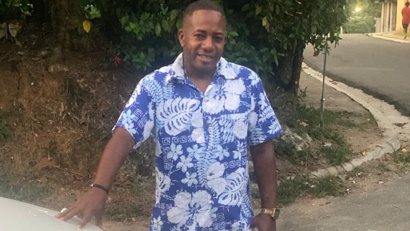La Fiscalía de San Cristóbal informó este domingo que continúa investigando la muerte de Miguel Antonio Valenzuela, conocido como “Miguelito”, a pesar de que el informe preliminar de la autopsia establece que falleció a causa de una infección por leptospirosis que le provocó una trombocitopenia o disminución severa de plaquetas. En un comunicado, el Ministerio Público explicó que el examen realizado por el Instituto Nacional de Patología Forense (Inacif) determinó de manera preliminar que la causa del fallecimiento fue un proceso infeccioso bacteriano. Sin embargo, precisó que las investigaciones permanecen abiertas debido a las denuncias de familiares, quienes aseguran que Valenzuela habría sido víctima de maltratos mientras permanecía bajo custodia policial. Según el informe oficial, el hombre, de 44 años, fue detenido el 8 de julio por agentes de la Policía Nacional, acusado de vender rifas de manera irregular utilizando un dispositivo electrónico. Permaneció bajo custodia hasta el 13 de julio, cuando un tribunal ordenó su libertad. La Fiscalía indicó que, tras salir del Palacio de Justicia, Valenzuela comenzó a sentirse mal y fue trasladado al Hospital Regional Docente Juan Pablo Pina, donde presentó dificultad respiratoria, sarpullido, petequias y hemorragia conjuntival. Posteriormente fue ingresado en la unidad de cuidados intensivos, donde falleció esa misma noche tras sufrir un paro cardiorrespiratorio. El Inacif informó que la autopsia evidenció daños en distintos órganos compatibles con un proceso inflamatorio y que las pruebas de laboratorio confirmaron la presencia de la bacteria causante de la leptospirosis, sustentando de forma preliminar la causa de muerte. No obstante, el Ministerio Público reiteró que continuará desarrollando las diligencias investigativas para esclarecer las circunstancias del caso y determinar si existen responsabilidades vinculadas a las denuncias realizadas por los familiares. La muerte de “Miguelito” ha generado protestas en San Cristóbal, donde allegados, vecinos y organizaciones sociales exigen una investigación exhaustiva, al denunciar que el hombre presentó problemas de salud durante su detención y no habría recibido atención médica oportuna. Hasta el momento, las autoridades no han informado si el informe definitivo de la autopsia abordará las acusaciones de presunto maltrato bajo custodia policial.