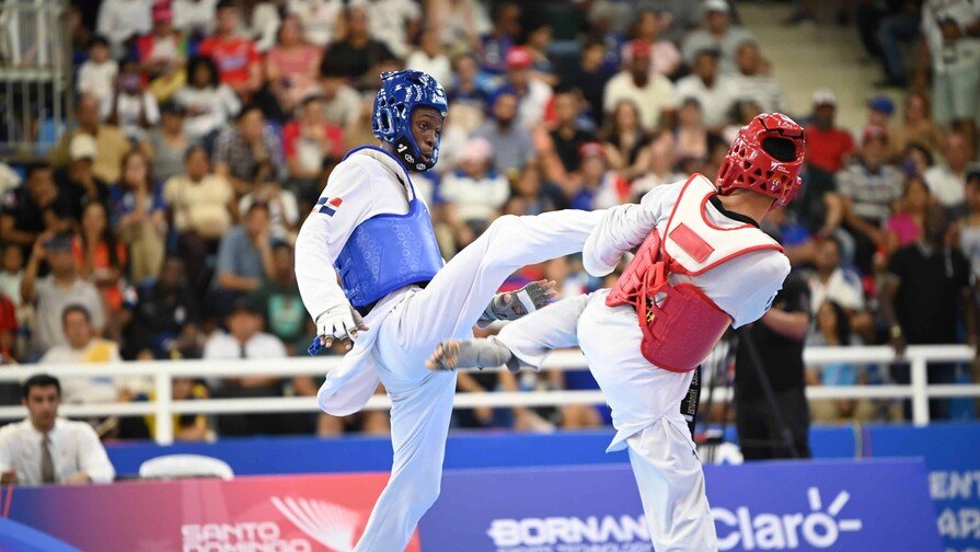 El dominicano Wilfrido de la Cruz otorgó este domingo la tercera medalla de oro a la representación de la República Dominicana en los XXV Juegos Centroamericanos y del Caribe Santo Domingo 2026, al imponerse en la final de los -54 kilos masculino del torneo de taekwondo. Camino al título De la Cruz venció en la final al hondureño Derek Midence por 2-0, en un combate disputado en el Pabellón de Combates del Centro Olímpico Juan Pablo Duarte. Para llegar al desenlace, derrotó primero al guatemalteco Diego Reyes y en semifinal superó al mexicano Sebastián Echavarría, mostrando solidez en cada presentación. Debut en el Ciclo Olímpico El joven atleta debutó en competencias del Ciclo Olímpico, convirtiéndose en parte del relevo generacional que toma la antorcha del taekwondo dominicano. Su triunfo refuerza la presencia del país en una disciplina que históricamente ha dado medallas en eventos regionales y mundiales. Balance dominicano Con este resultado, la delegación dominicana suma tres oros en la justa regional, tras los conseguidos por las judocas Ana Rosa y Esmeralda Damiano. La jornada dominical también fue histórica: la República Dominicana alcanzó las mil medallas acumuladas en la historia de los Juegos Centroamericanos y del Caribe, cifra lograda gracias a los aportes recientes en judo, taekwondo y esquí náutico. Las mil medallas El país inició Santo Domingo 2026 con 993 preseas acumuladas. El sábado sumó cinco más y este domingo agregó dos bronces de Francesca Pigozzi en esquí náutico y el oro de De la Cruz, alcanzando la marca simbólica de las 1,000 medallas. Pigozzi se destacó en figuras femenino, con 1,870 puntos, detrás de las colombianas Daniela Verswyvel (oro, 7,310) y Martina Piedrahita (plata, 3,710). En salto femenino, volvió a subir al podio con 18.5 metros, en otra competencia dominada por Colombia.